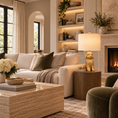 Load image into Gallery viewer, Cavadoodle lamp with a sculptural gold dog base and cream linen shade on a wooden side table beside a cream sofa in an elegant living room.
