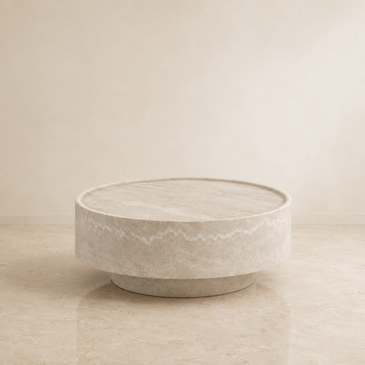 A round, low-profile coffee table with a textured stone or concrete finish in a warm beige-gray color, set against a matching beige background.