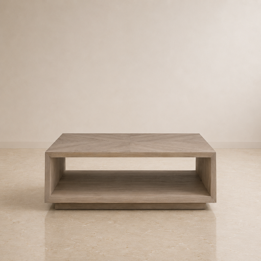 A modern low coffee table with a light gray wood finish and an open lower shelf, set against a minimalist beige wall and floor.