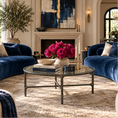 Load image into Gallery viewer, A luxury living room featuring a curved arrangement of deep blue velvet sofas, a round glass-top coffee table, a textured beige rug, and a vibrant pink floral arrangement in the center.
