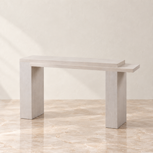 A modern light gray console table with a rectangular top and thick block legs, shown in a minimalist room setting with a beige wall and marble floor.