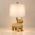 Load image into Gallery viewer, Gold Corgi Lamp with sculptural dog-shaped base and white fabric shade on a beige marble tabletop.
