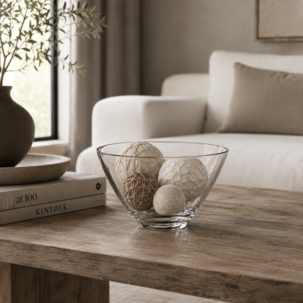 Crystal bowl filled with decorative balls on a wood coffee table in a neutral modern living room