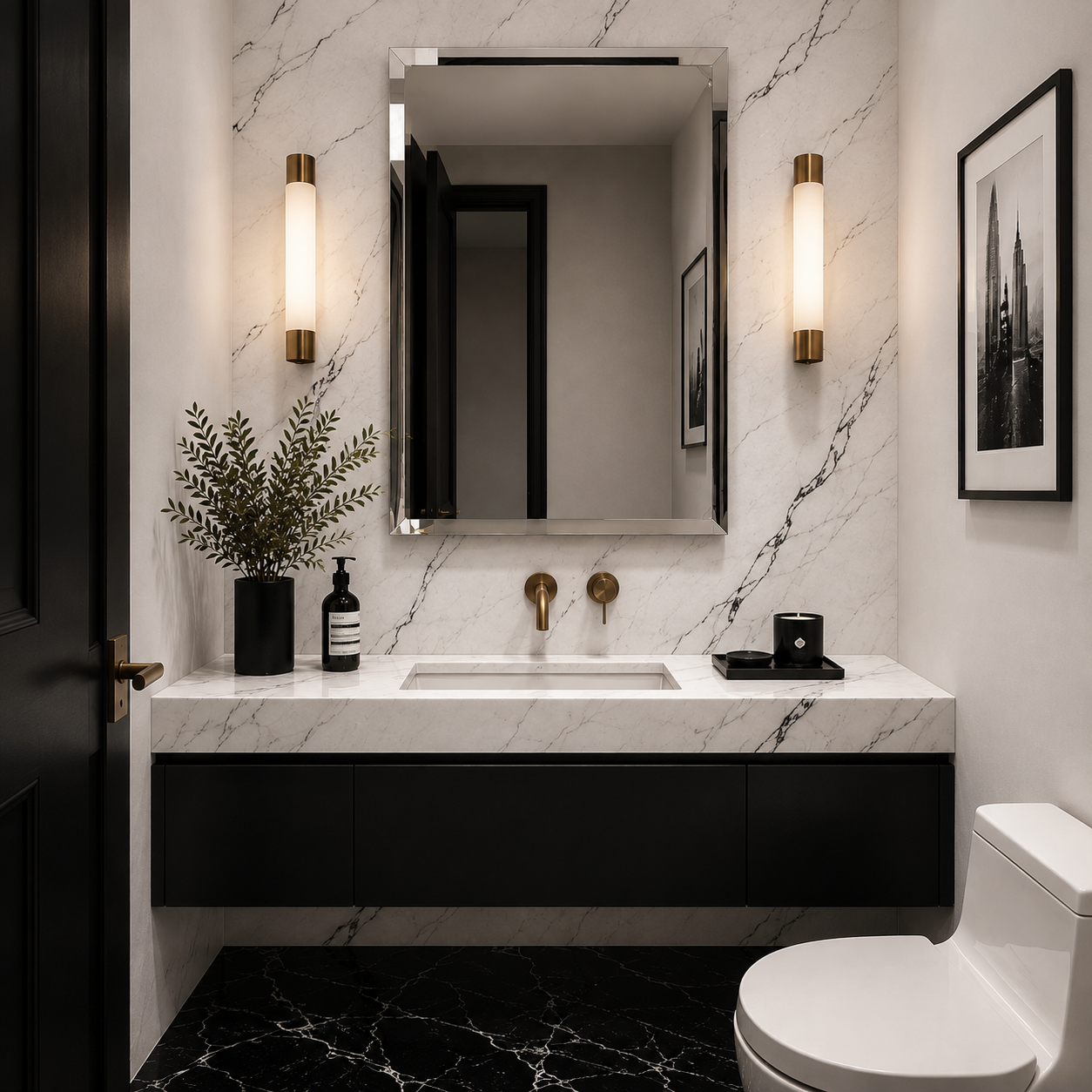 A modern bathroom vanity setup with a white marble countertop and sink, black floating cabinets, gold wall-mounted fixtures, a large frameless mirror, and matching wall sconces. A black marble floor, white toilet, framed black-and-white artwork, and a potted green plant are visible in the room.