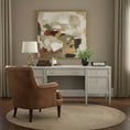 Load image into Gallery viewer, A styled home office scene featuring a white writing desk with drawers, a brown leather armchair, a round jute rug, and a window with beige curtains.
