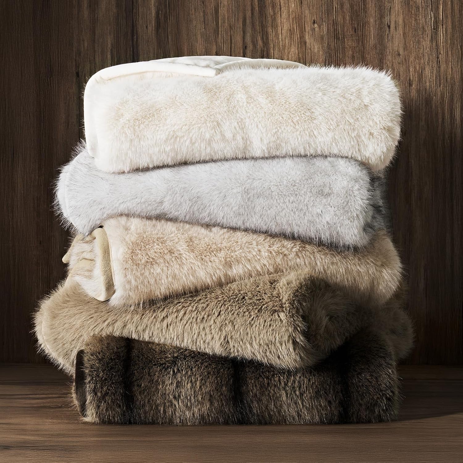 Luxury Faux Fur Throw folded and on top of a pile of other throw blankets on a shelf