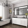 Load image into Gallery viewer, framed mirror above sinks in bathroom with a tub and a chandelier
