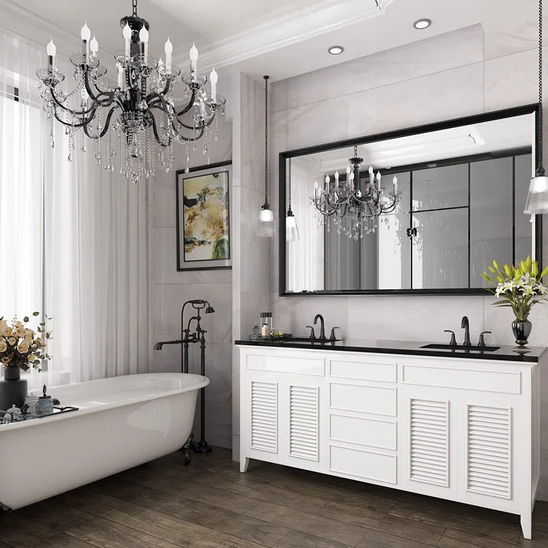 framed mirror above sinks in bathroom with a tub and a chandelier