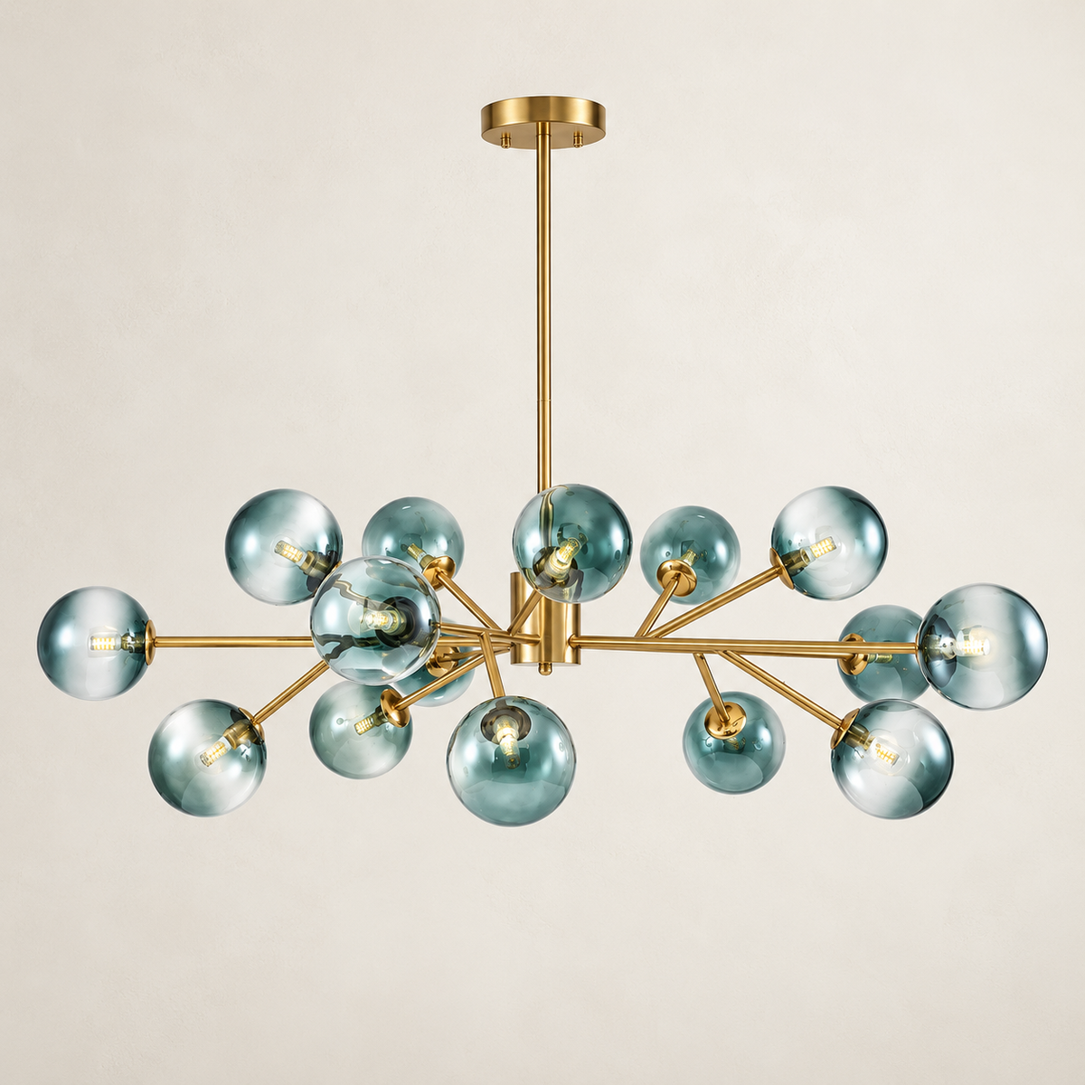 A modern multi-light chandelier with a brushed gold metal frame and translucent smoky blue glass globes, suspended from a matching gold ceiling canopy against a warm off-white background.