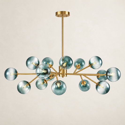 A modern multi-light chandelier with a brushed gold metal frame and translucent smoky blue glass globes, suspended from a matching gold ceiling canopy against a warm off-white background.