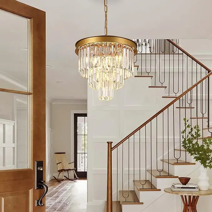 Gold chandelier with three tiers of elongated crystals and matte black metal frame in modern entryway