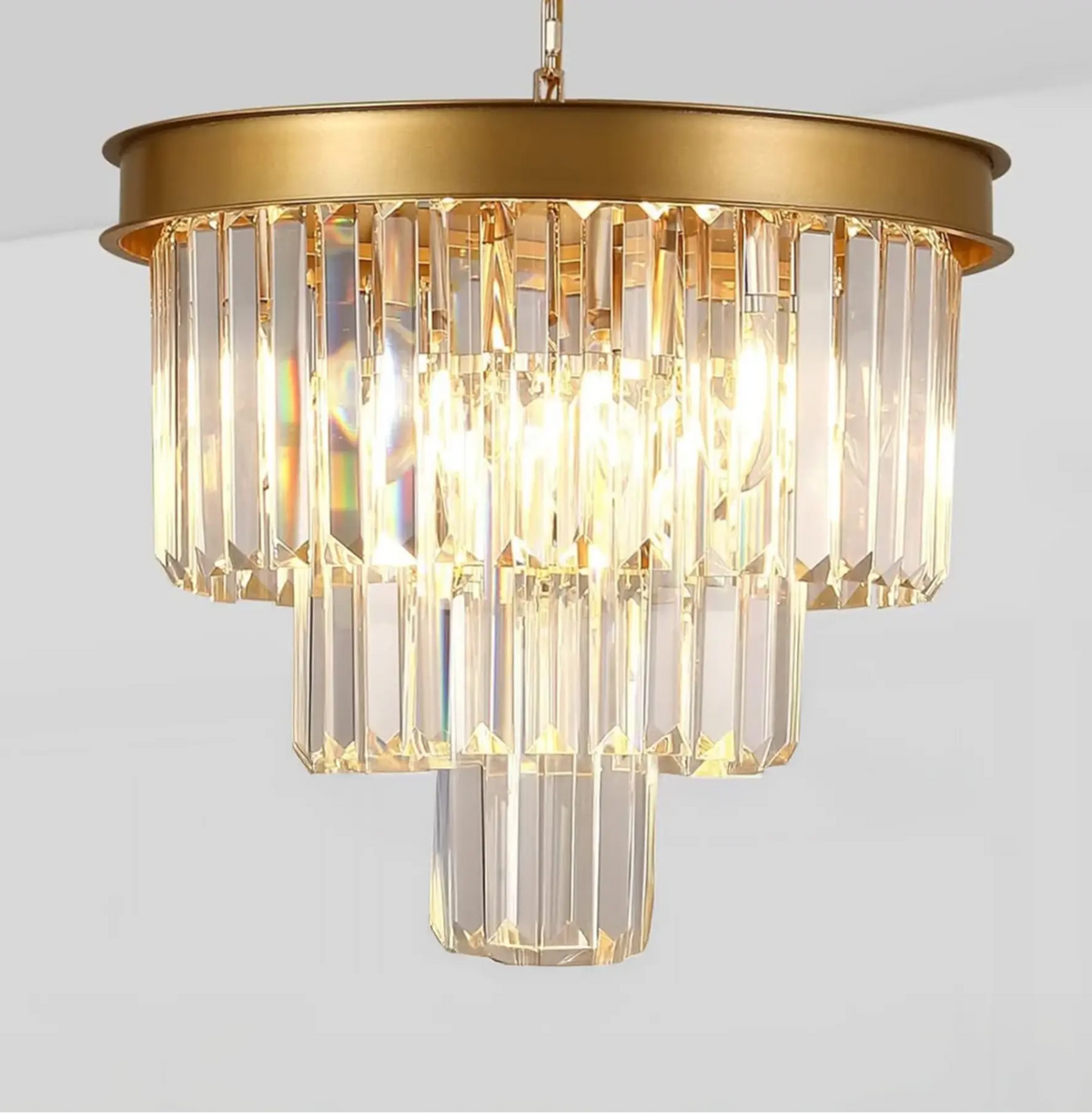 Three-tier gold chandelier with elongated multi-angled crystal bars and matte black metal frame on white background