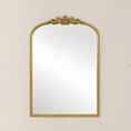 Load image into Gallery viewer, An ornate arched wall mirror with a decorative gold frame, featuring a sculpted floral crest at the top and a rope-textured border, shown against a light beige background.
