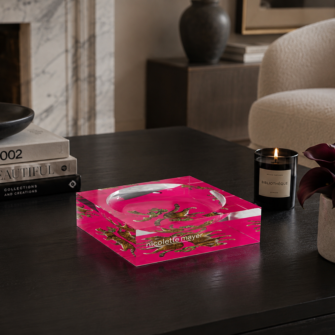 Hot pink catchall tray styled on a black table with books and candle