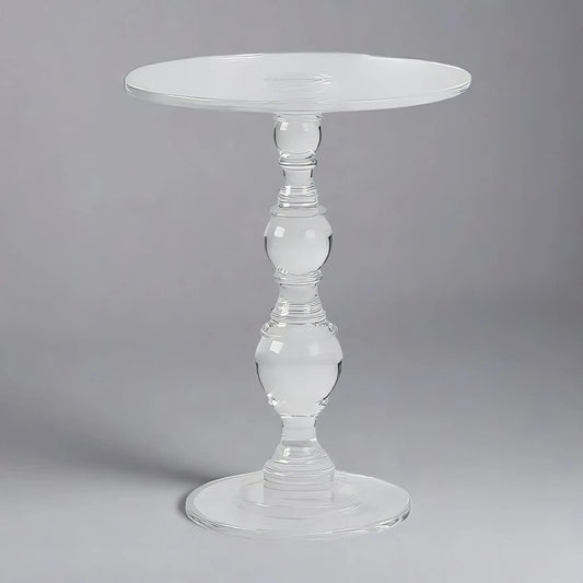 A clear table with a transparent, round glass top and an ornate pedestal base is set against a gray background, adding a modern touch to the decor is the ACRYLIC END TABLE from House of Effy.