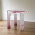 Load image into Gallery viewer, A modern ACRYLIC SIDE TABLE from the House of Effy, featuring a pink hue, positioned on a wooden floor and placed against a plain wall. The table boasts an unconventional, contemporary design with artistic, asymmetrical legs.
