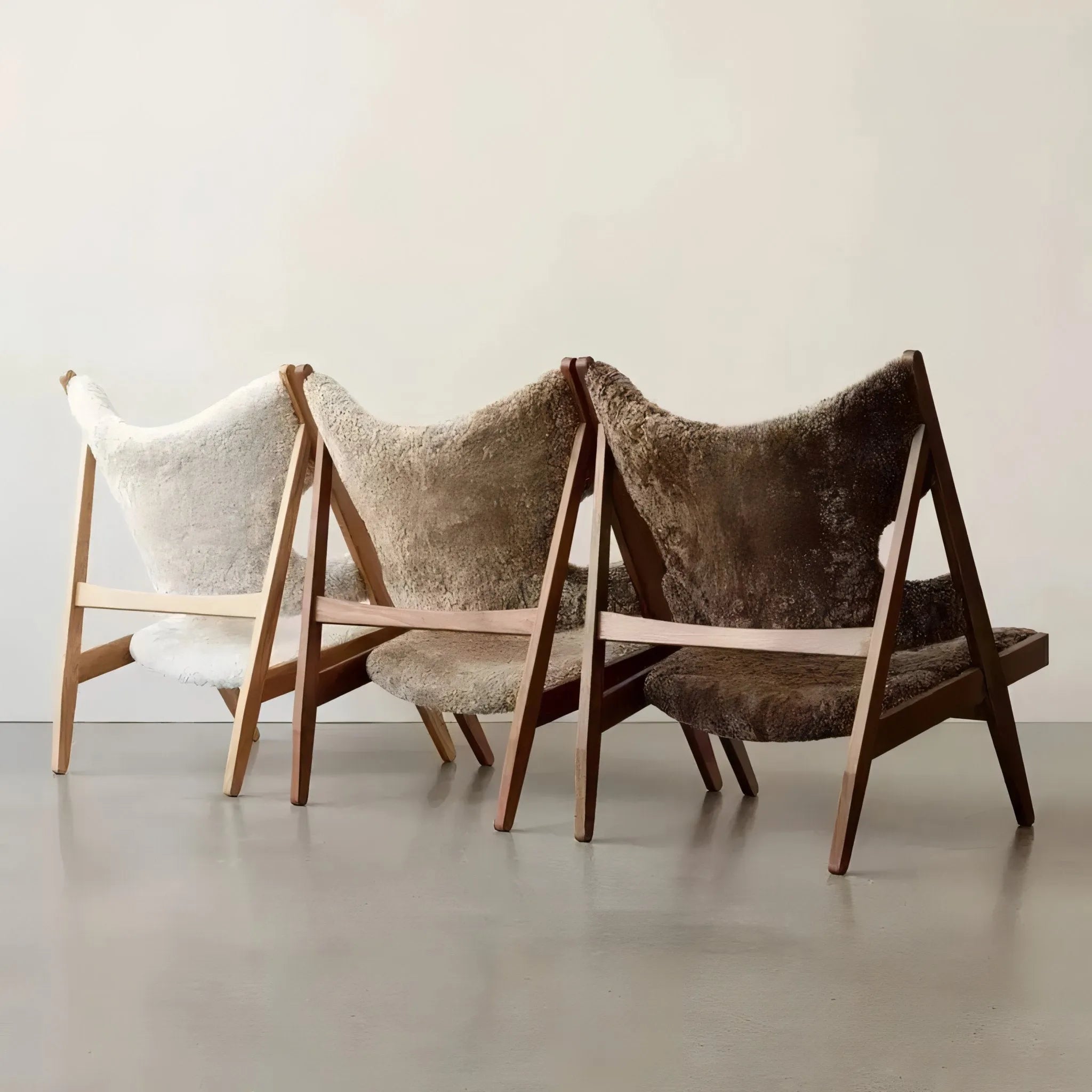 Three House of Effy MINIMALIST CHAIRS with wooden frames and plush, textured cushions in white, tan, and brown, aligned side by side against a neutral background feature a contemporary chair design.