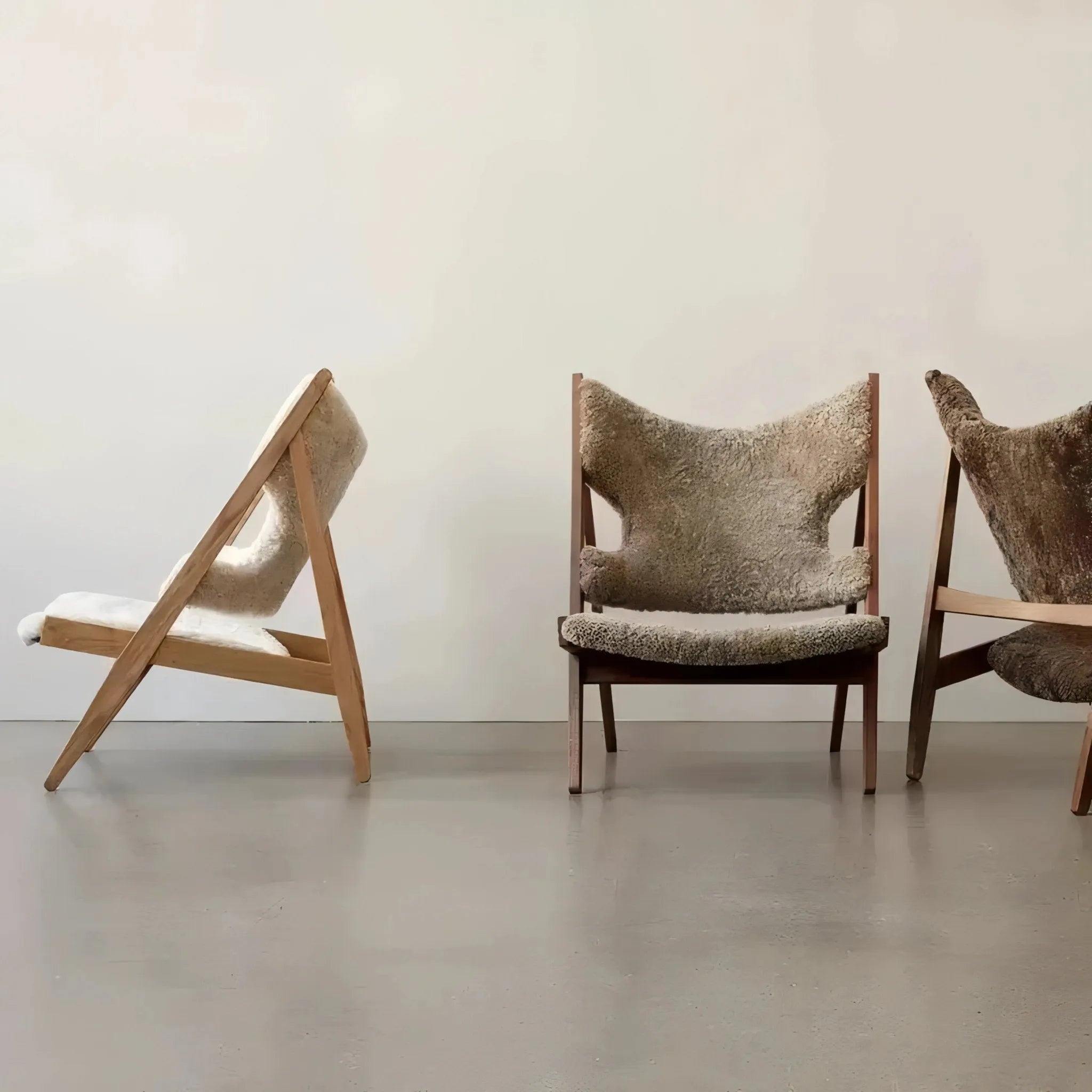 Three House of Effy minimalist chairs with sleek design, one tipped over, standing on a concrete floor against a plain wall.