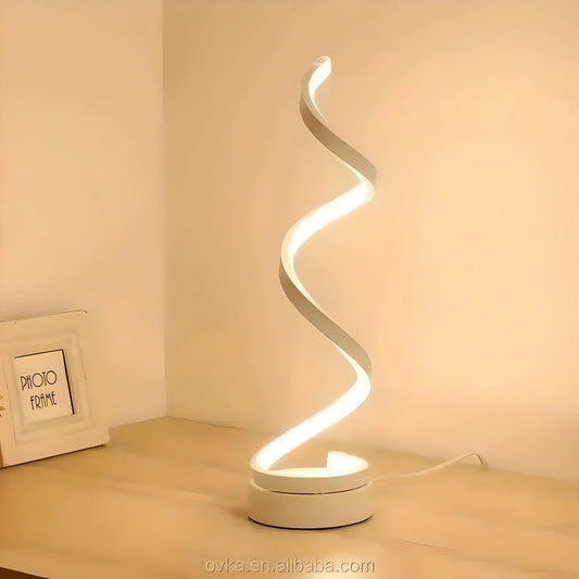 A modern House of Effy Twisty LED White Table Lamp illuminates a corner, casting a soft glow next to a photo frame on a desk.