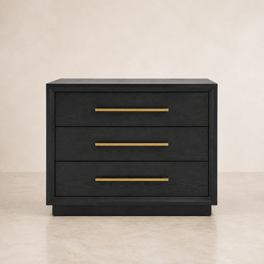 A three-drawer nightstand or side table in a dark black wood finish with slim horizontal gold metal handles, set against a neutral beige background.