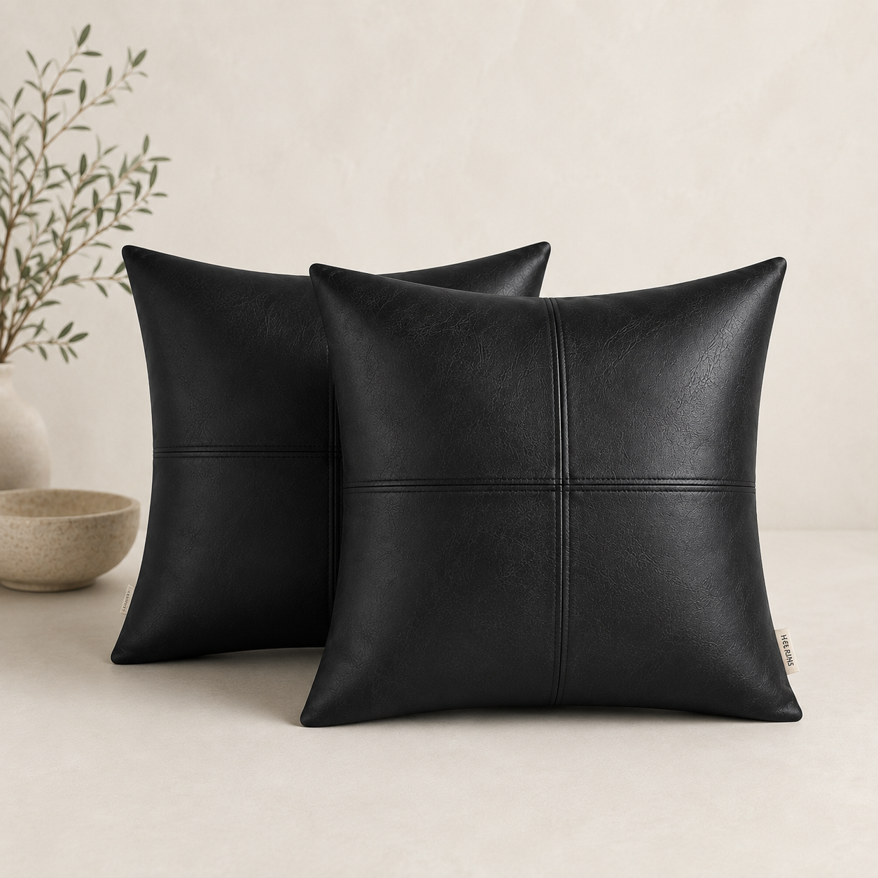 black leather pillow covers next to bowl and faux tree