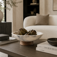 Load image into Gallery viewer, marble bowl with a wooden base holding artichokes, styled on a dark wood coffee table in a modern living room setting.
