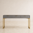 Load image into Gallery viewer, A modern console table with a gray shagreen top and three drawers, supported by a slim gold metal frame, set against a neutral beige background.
