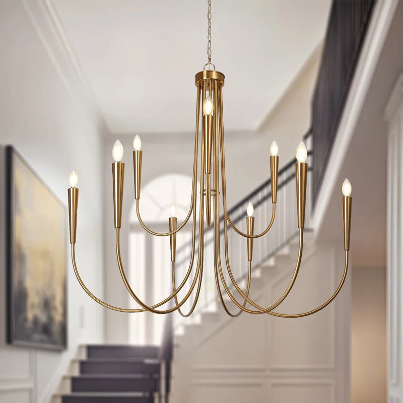 modern gold chandelier in foyer with staircase behind it