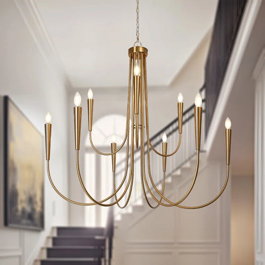 modern gold chandelier in foyer with staircase behind it