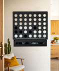 Load image into Gallery viewer, Life size wall mounted Four in a Row game with black and white discs in a minimalist living space with wooden furniture
