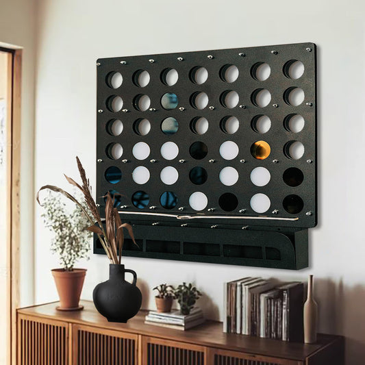 Life size black wall-mounted Four in a Row game with gold and black game pieces above wooden sideboard with decor