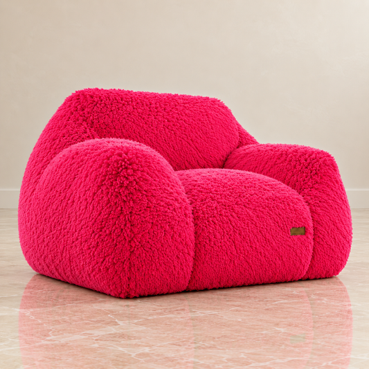 pink puff floor chair fuzzy boucle armchair with rounded, cloud-like cushions, set against a neutral beige wall and a pink marble floor