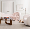 Load image into Gallery viewer, Pink Throw Blanket by UGG draped over a cured sofa in a living room next to a floor lamp and across from a coffee table and a boucle swivel chair
