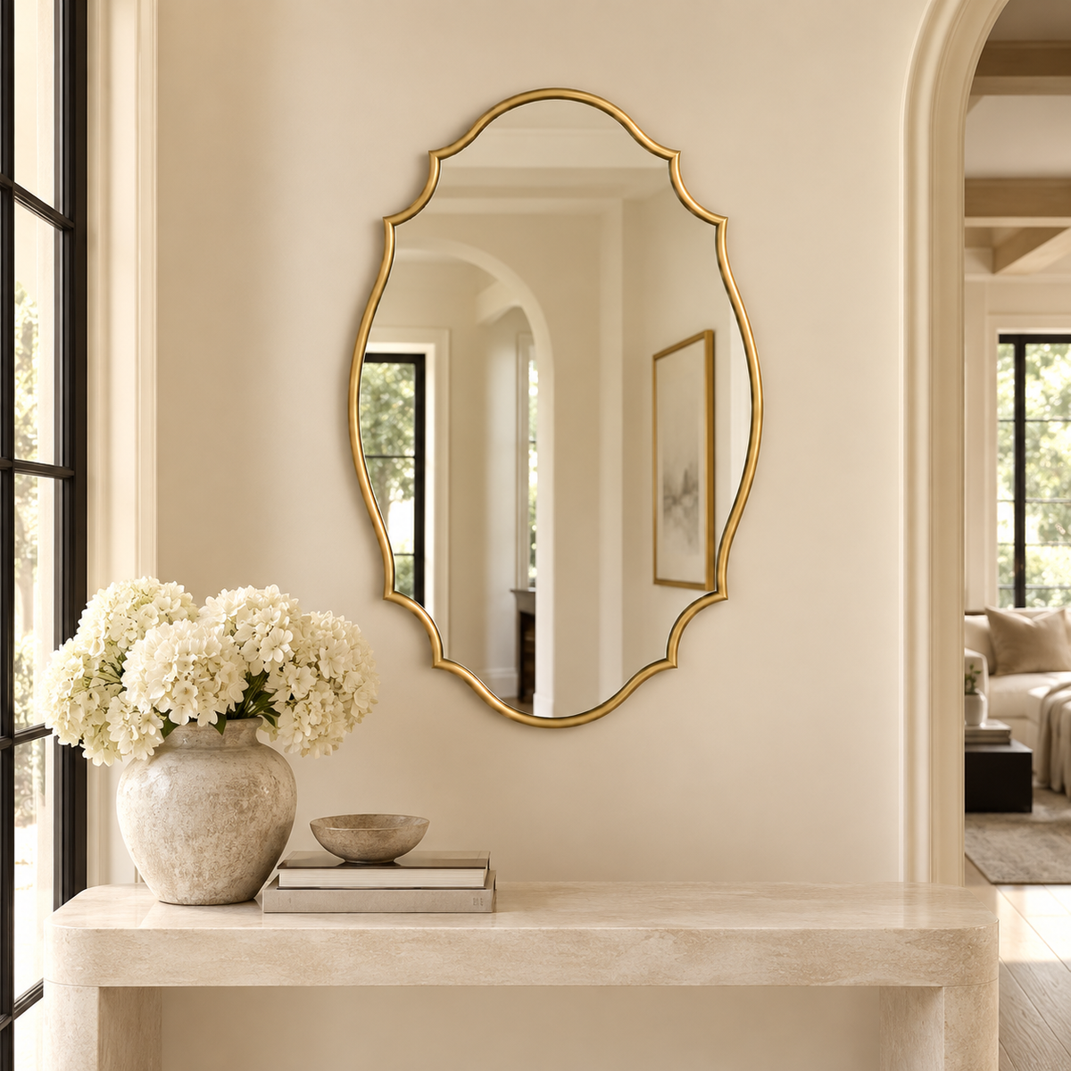 scalloped mirror in foyer above a console table with books and a vase with flowers