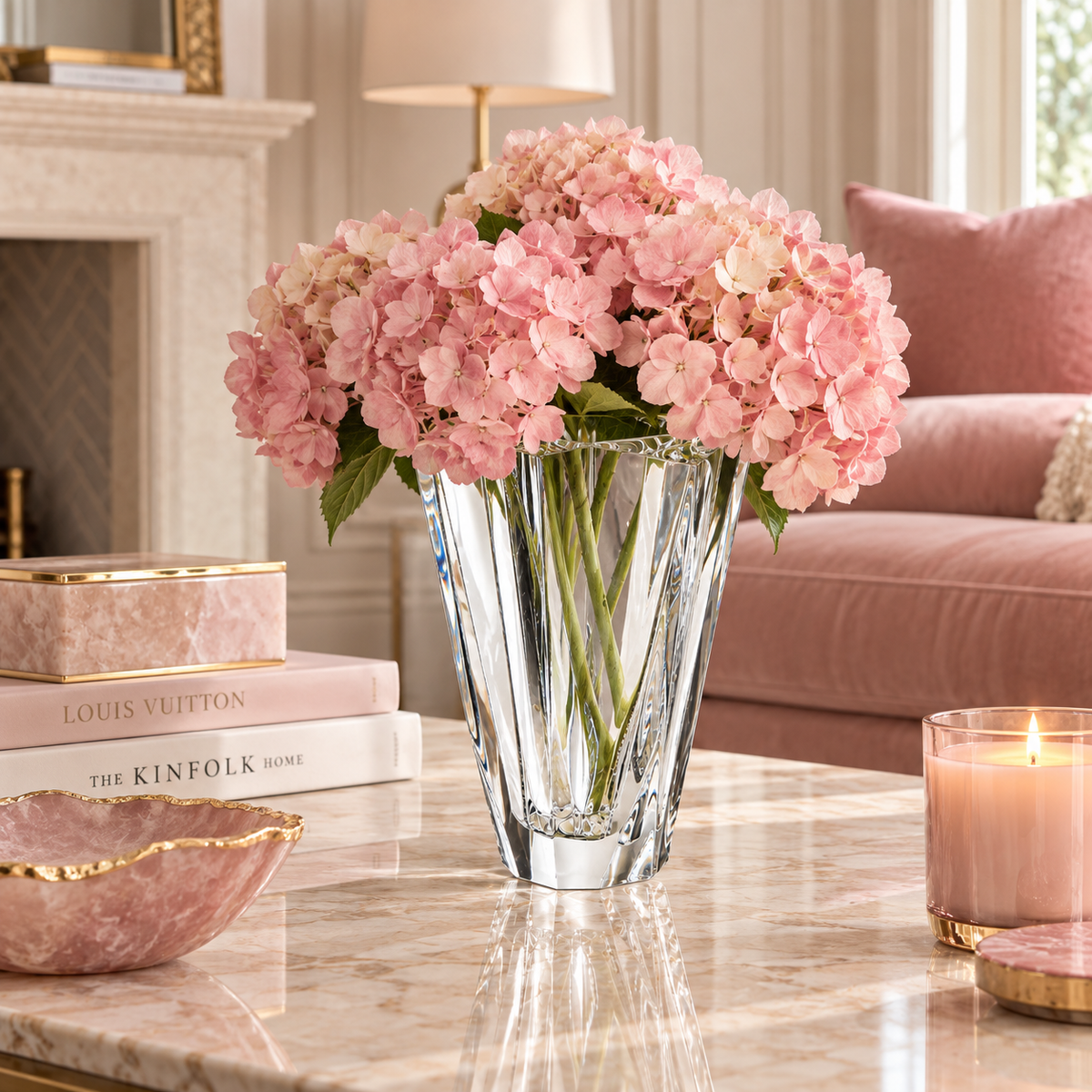 Shannon Crystal Vase by Orrefors with pink hydrangeas on a marble coffee table in an elegant living room with blush pink accents.