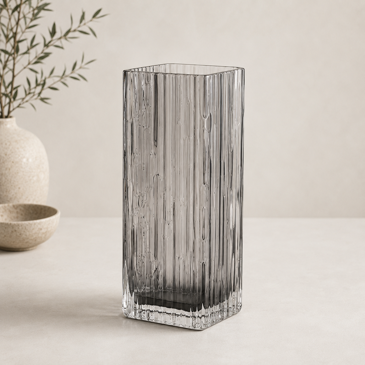 Smoked crystal vase with a tall rectangular shape and textured ribbed glass displayed against a neutral beige background.