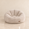 Load image into Gallery viewer, A round, tufted sofa chair in a textured beige fabric, set against a matching beige marble floor and wall background.
