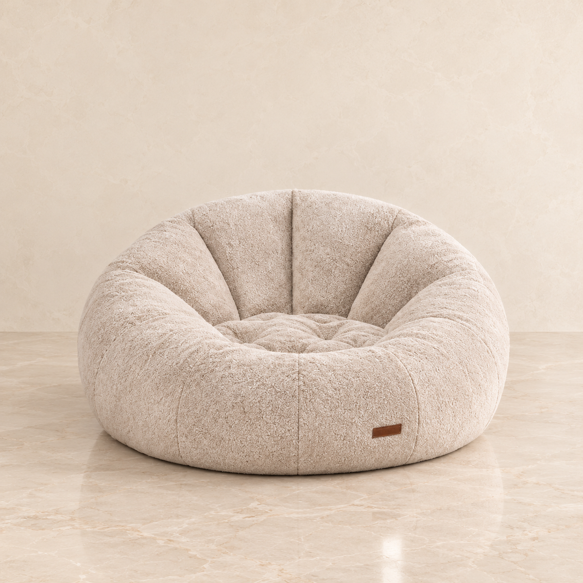 A round, tufted sofa chair in a textured beige fabric, set against a matching beige marble floor and wall background.