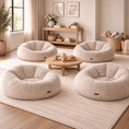 Load image into Gallery viewer, Four round plush floor poufs in a light beige bouclé fabric arranged around a small wooden coffee table on a large woven area rug in a bright, neutral-toned living room.
