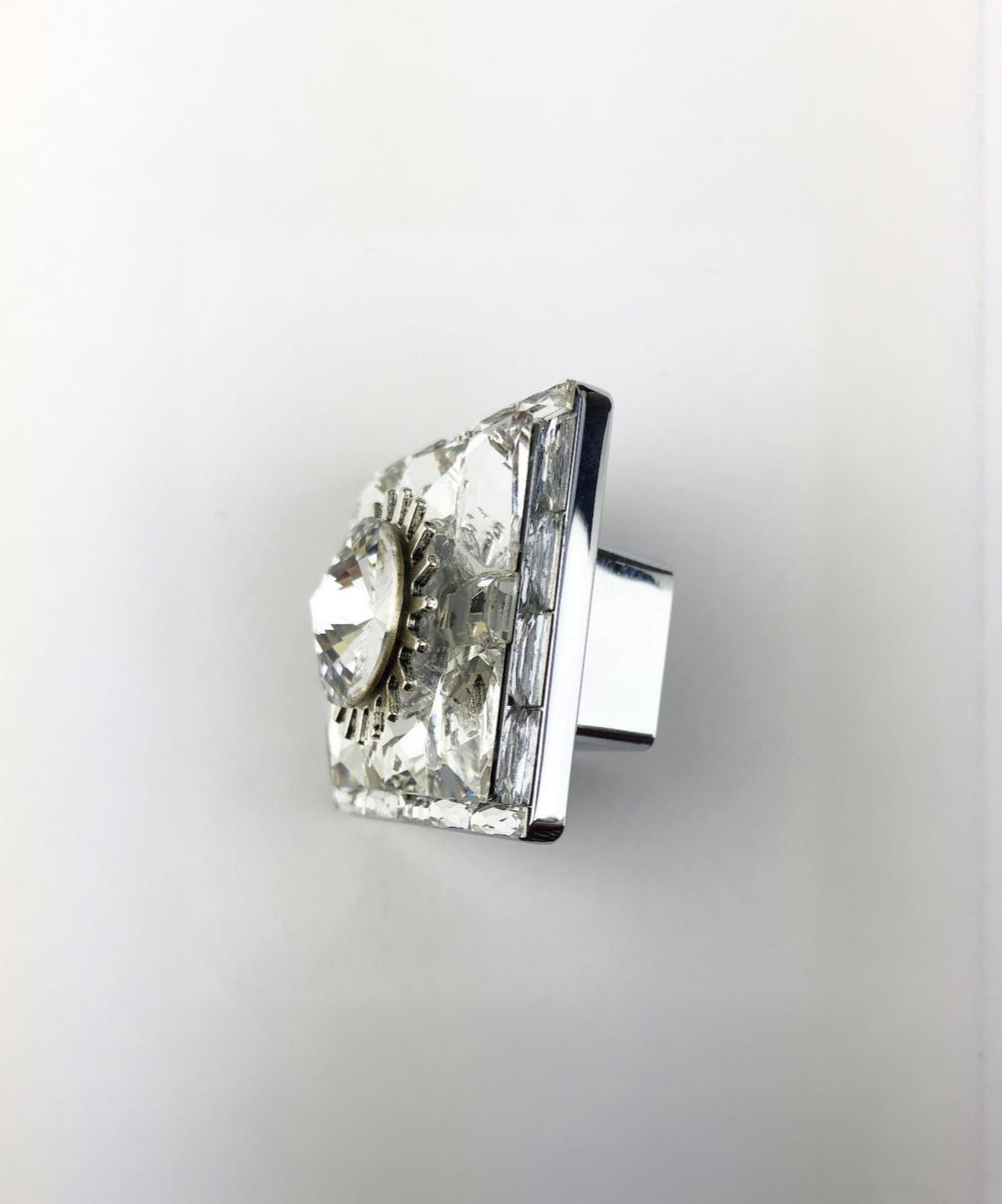 Square crystal knob with faceted center gem and reflective silver base on a white background
