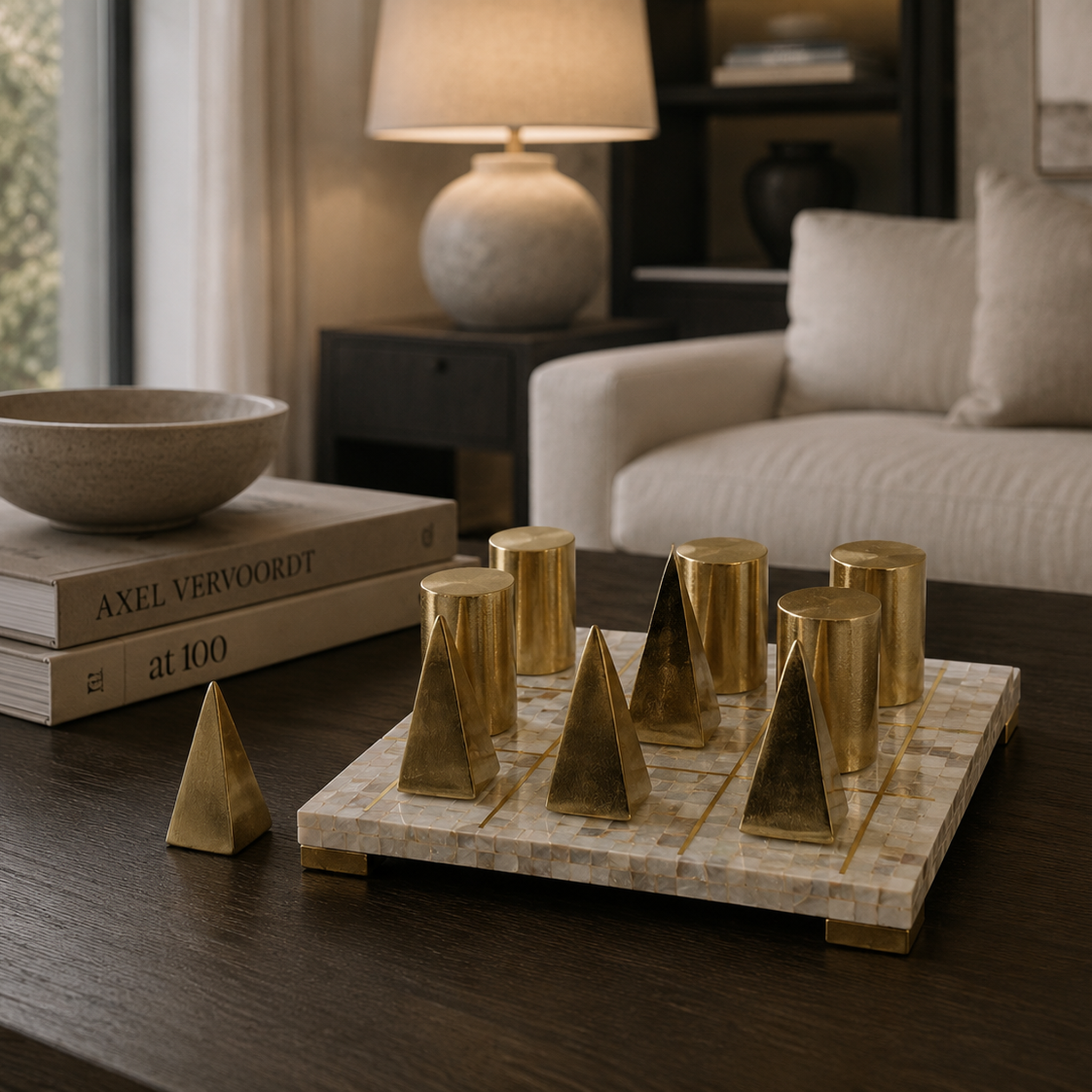 A gold geometric chess set with cylindrical and triangular pieces arranged on a mosaic board on a dark wooden table, with a softly blurred living room background.