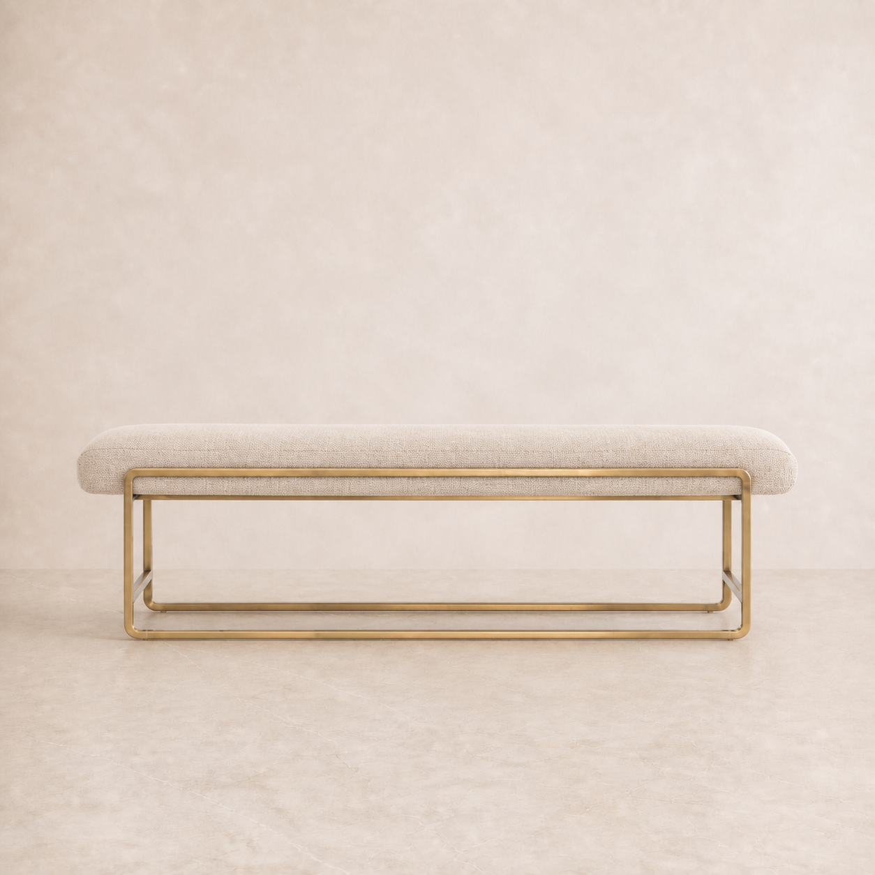A modern upholstered bench with a light beige fabric seat and a polished gold metal frame, set against a matching beige textured background.