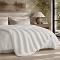 Load image into Gallery viewer, A plush white blanket draped over a neatly made bed in a softly lit bedroom. The scene includes matching pillows, a bedside lamp, books, wall art, and a window with natural light.
