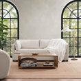 Load image into Gallery viewer, white blanket on sofa which is next to large windows and across from coffee tables
