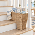 Load image into Gallery viewer, wicker basket for stairs with a triangular shape, styled on a wooden staircase with folded blankets, a throw pillow, and a magazine
