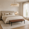 Load image into Gallery viewer, A beautifully styled bedroom featuring a bed dressed in neutral beige linens, a matching upholstered headboard, a woven brown bench at the foot, a large glass chandelier, and sheer curtains by a bright window.
