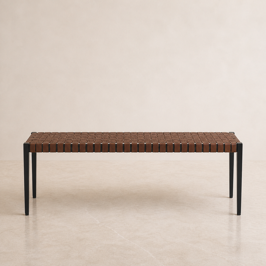A rectangular coffee table with a woven brown leather top and slim black metal legs, set against a neutral beige background.
