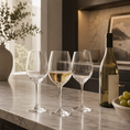 Load image into Gallery viewer, wine glass set on a marble countertop in a kitchen setting, with one glass partially filled with white wine and a wine bottle beside it.
